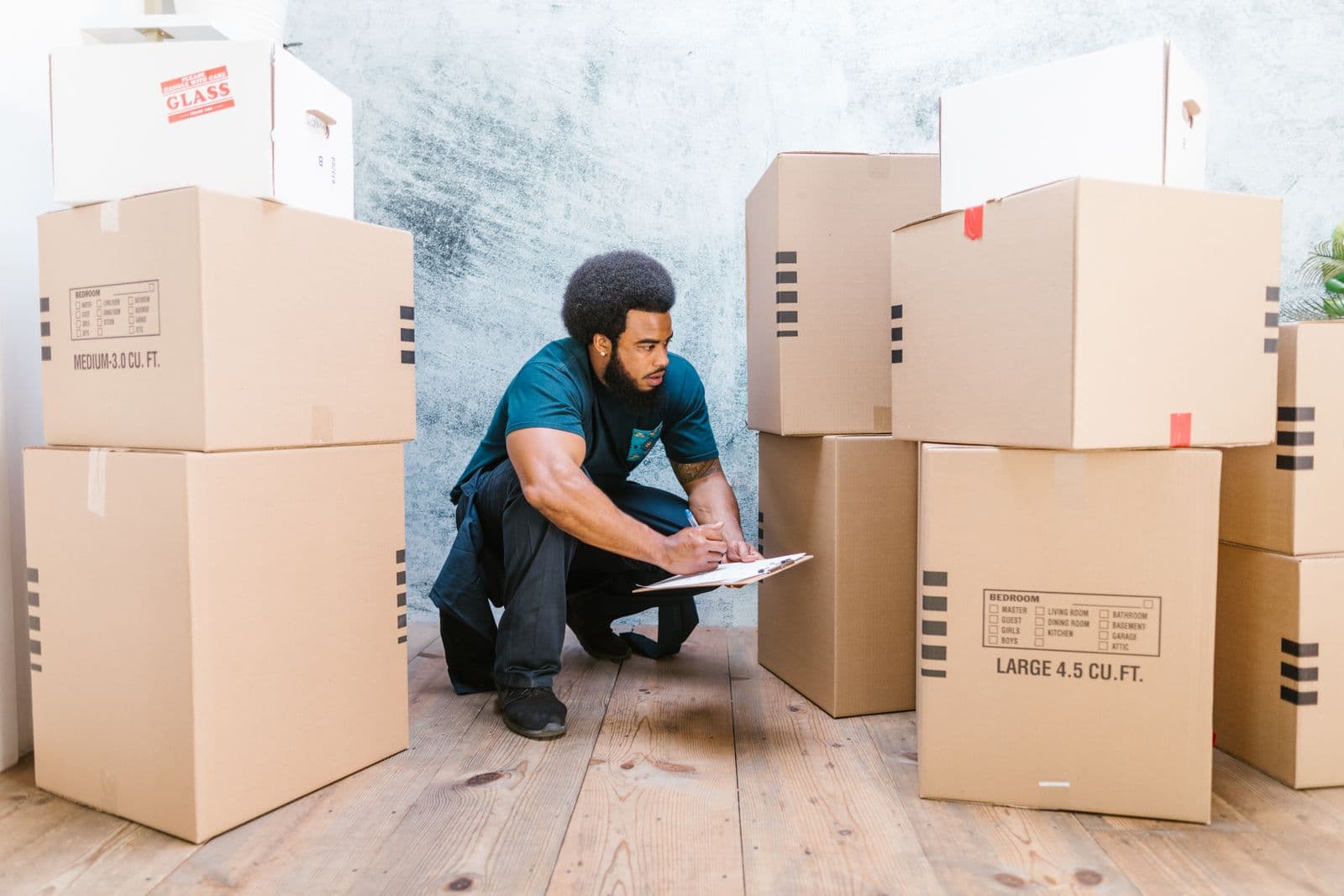 Mover checking a clipboard beside stacked boxes