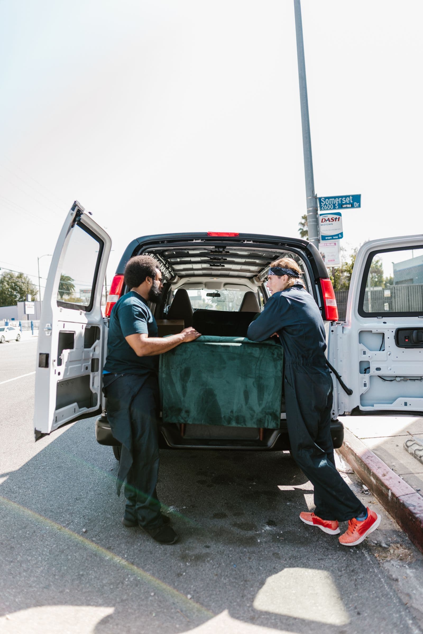 Two movers loading a sofa into a van